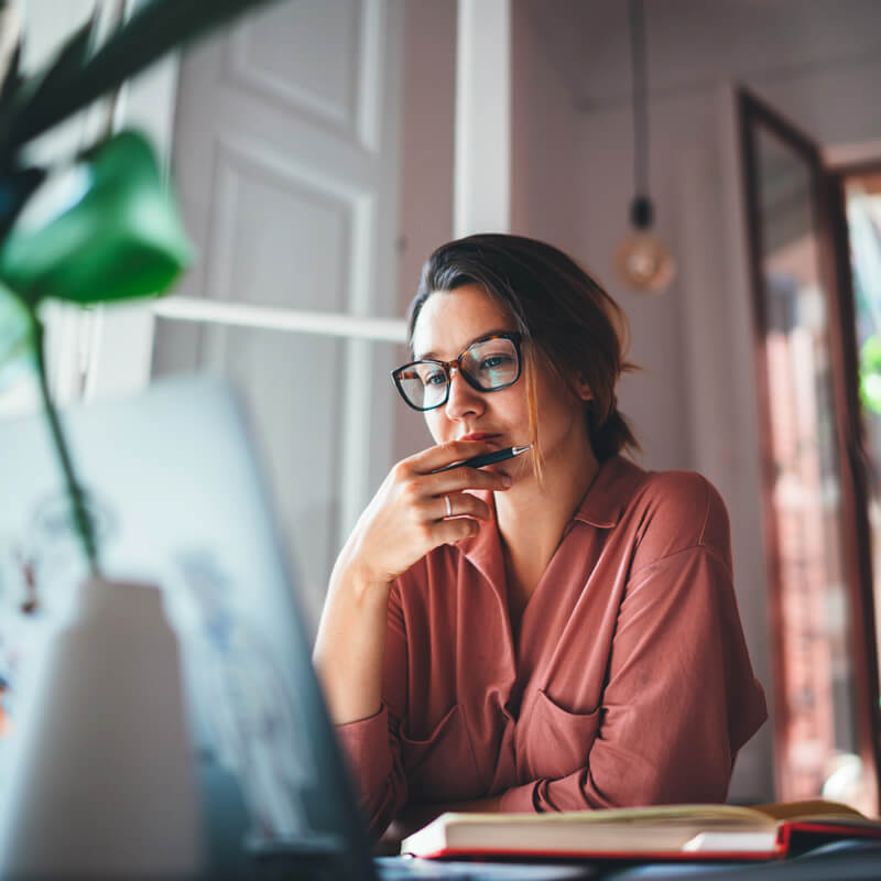 A woman considering her options looking at her computer screen.