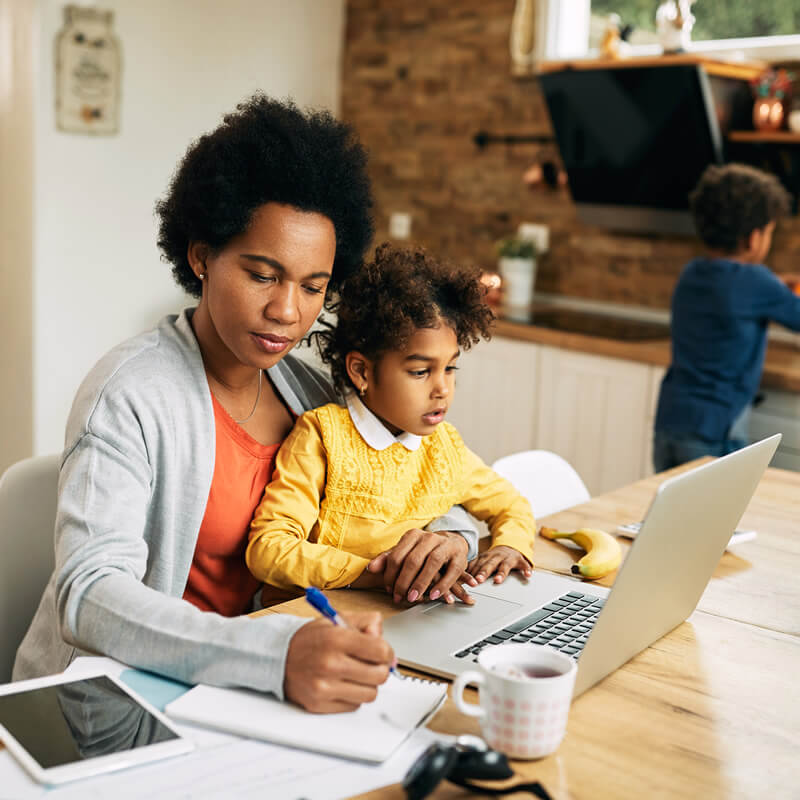 A woman working at a desk with a child on her lap.