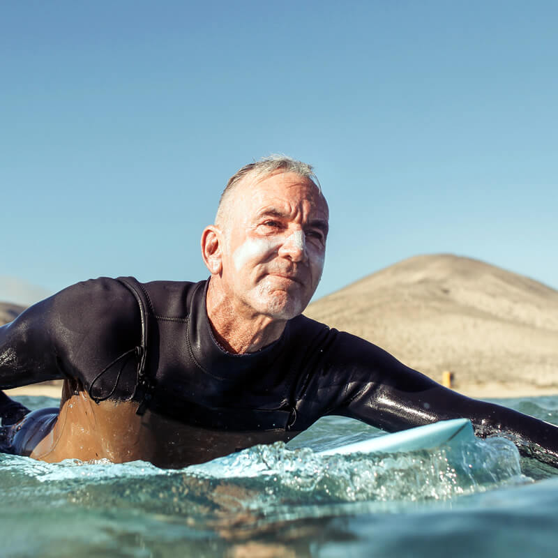 A retired man surfing.