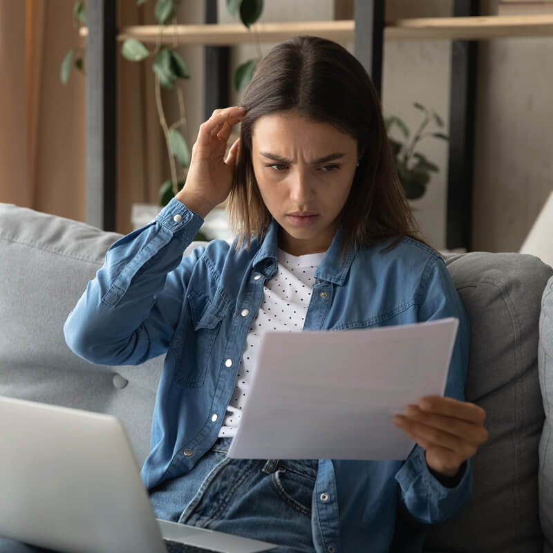 A serious woman looks at paperwork while on her sofa