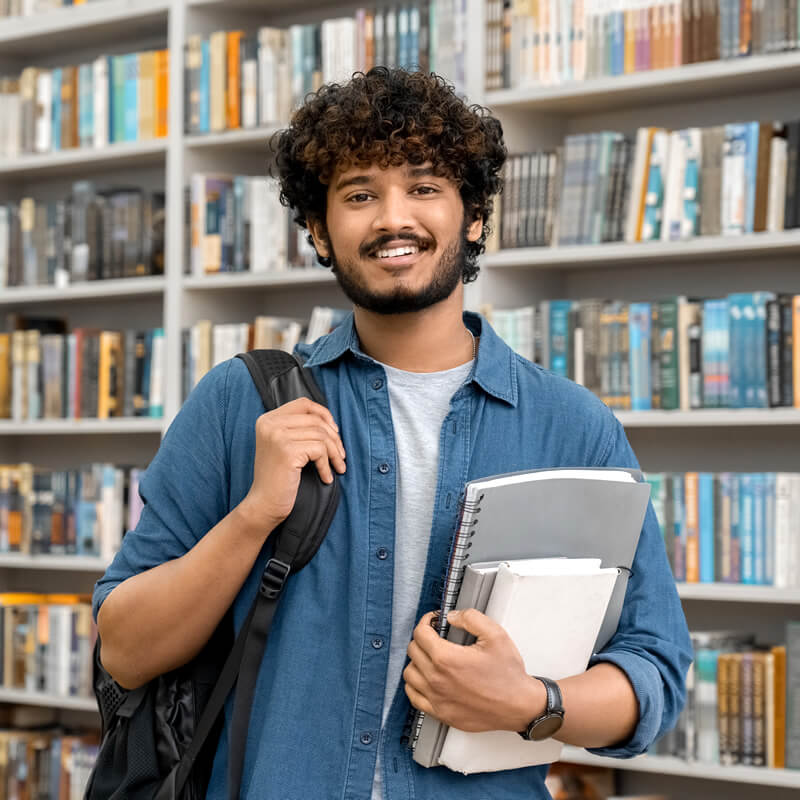 A happy student standing in a library.