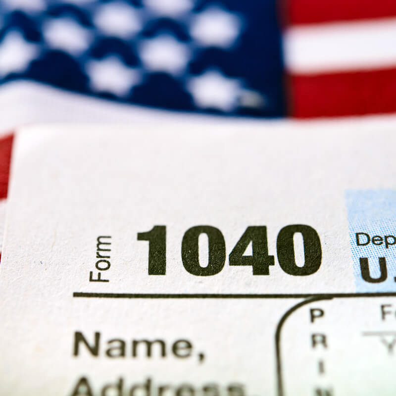 A 1040 tax form against an American flag background