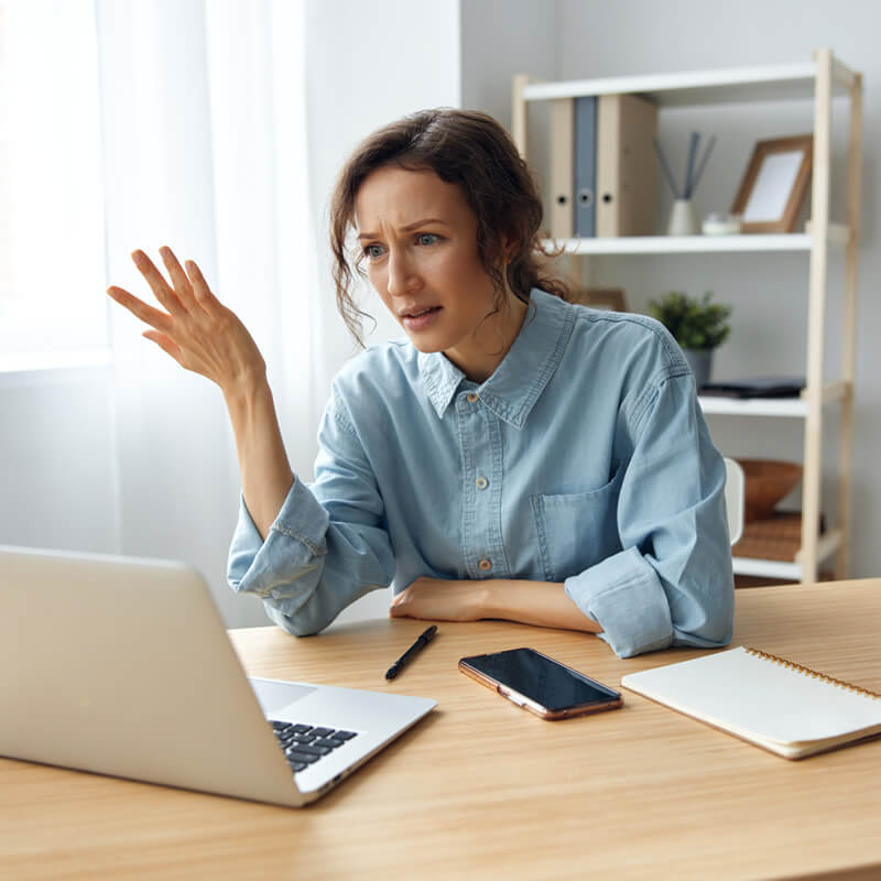 A frustrated woman sitting in front of a laptop computer.