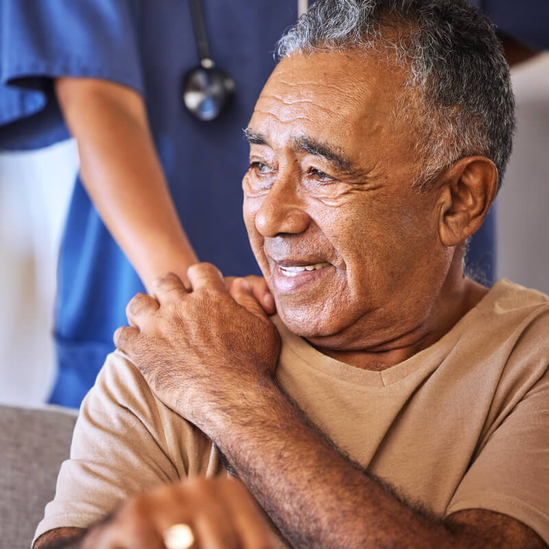 An older man is comforted by a healthcare worker.