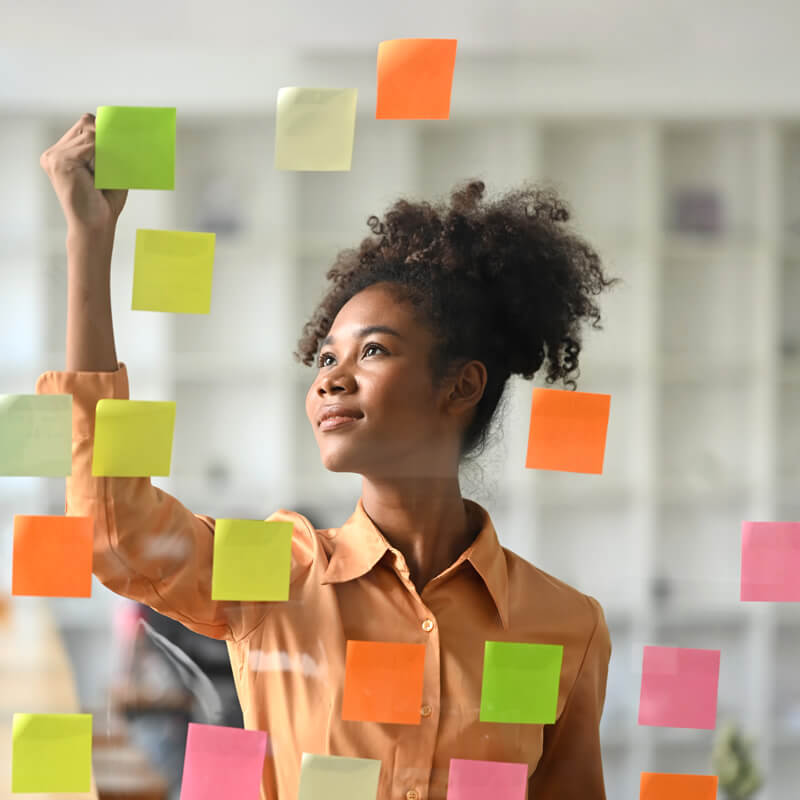 A woman creates a priority list with sticky notes.