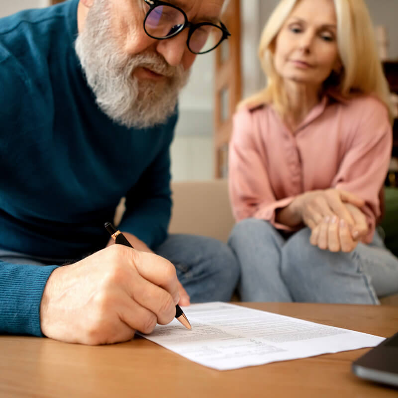An older man signs a document.