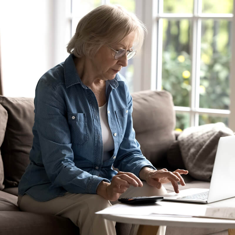 A woman reviews financial documents on a laptop