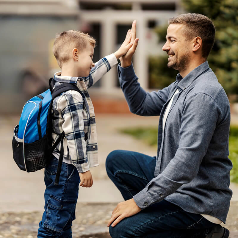 A father and son high five each other outside