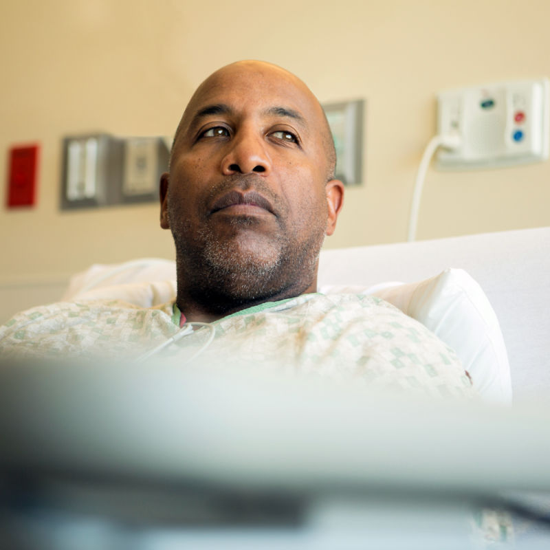 A worried man lies in a hospital bed.