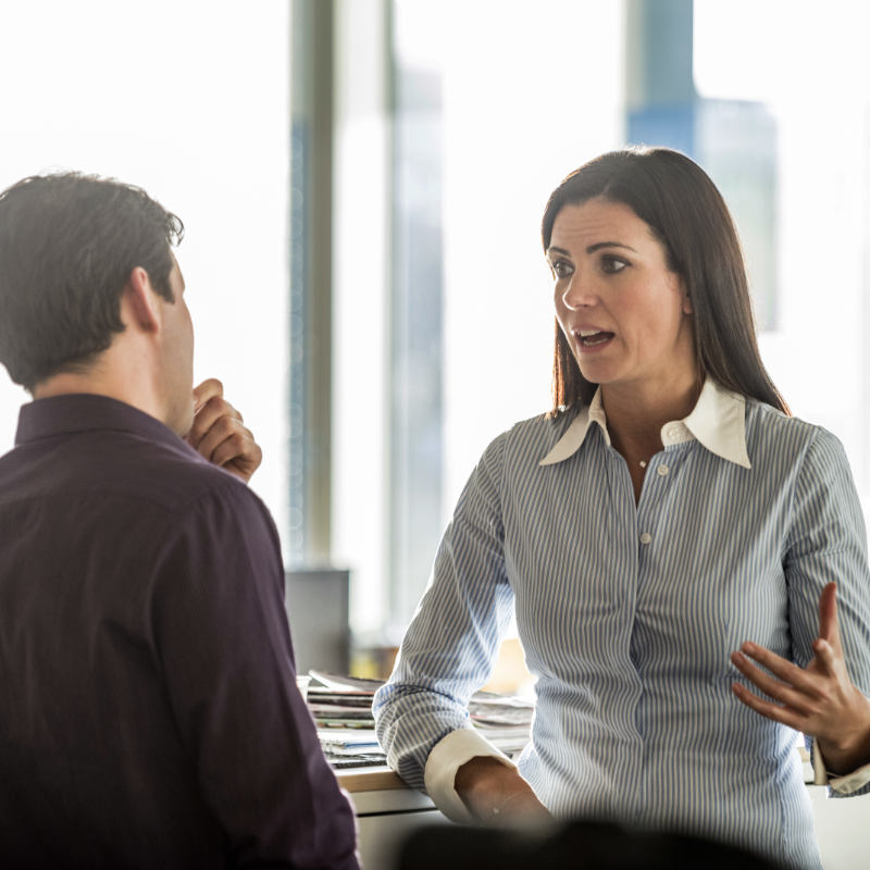 Two individuals having a heated discussion in a workplace setting.