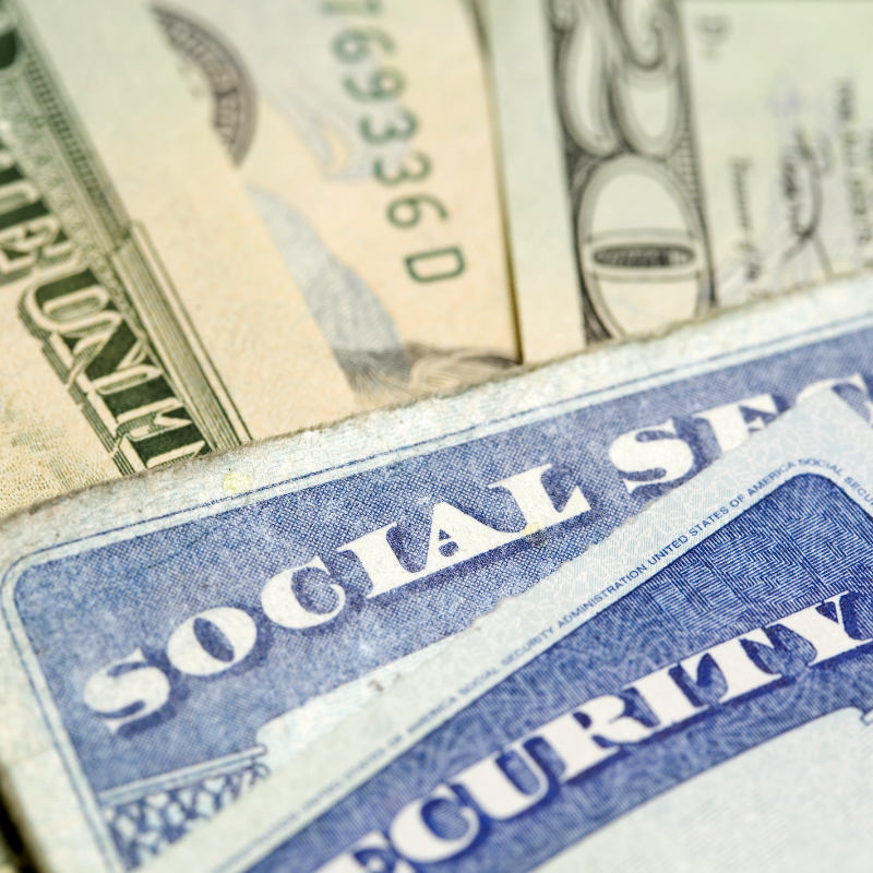 Social Security cards resting on a pile of twenty dollar bills