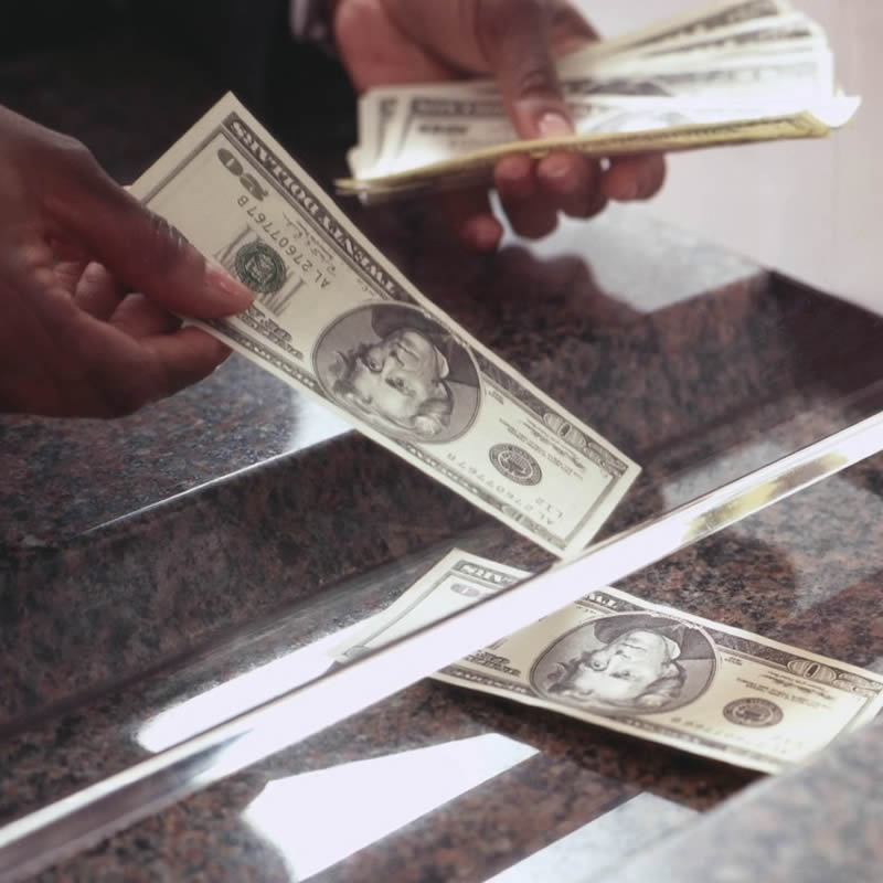 Bank Teller dispensing cash under bank window.