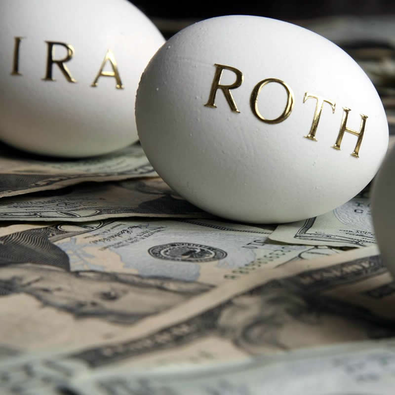 Two eggs (IRA and Roth on them) on top of money. 