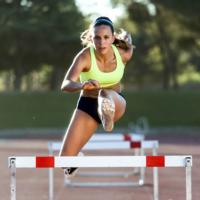 A woman jumps hurdles at a track meet.