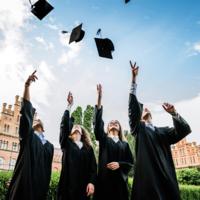 Four college students throwing caps into the air at graduation.