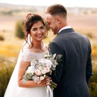 A groom and bride pose for a photo.