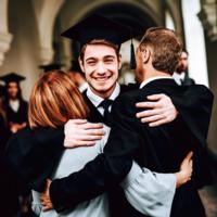 A new college graduate hugs his parents.