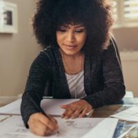 A woman takes notes while at her desk.