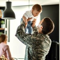 A soldier lifting his son into the air.