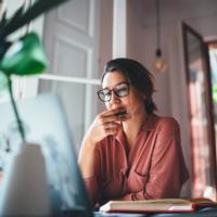 A woman considering her options looking at her computer screen.