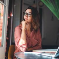 A woman thinking while looking out of a window.