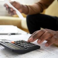 A person entering receipt figures into a calculator.