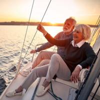 A retired couple on a sailboat at sunset.
