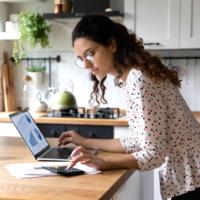 A woman updating her budget at her kitchen island.
