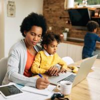 A woman working at a desk with a child on her lap.