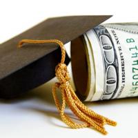 A mortar board leaning on a stack of money.