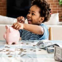 A child adding money to a piggy bank.
