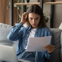 A serious woman looks at paperwork while on her sofa