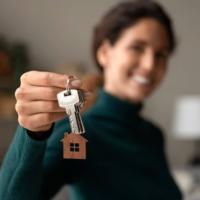 A set of keys to a home with a smiling woman.