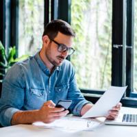 A calm man reviewing a document and sitting at a desk.