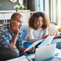 A couple reviews financial statements at home.
