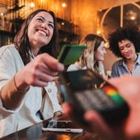 A person pays for meal at a restaurant with friends.