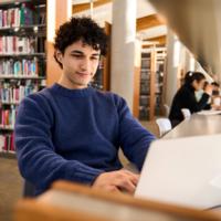 A student working on a laptop in a library.