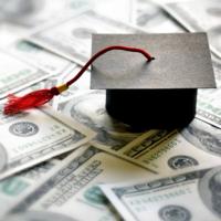 A college mortar board cap on a pile of money.