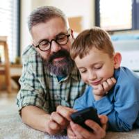 A boy and his dad looking at a smartphone