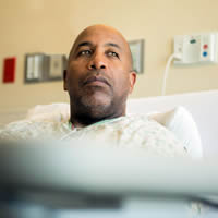 A worried man lies in a hospital bed.