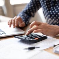 A person using a calculator and computer